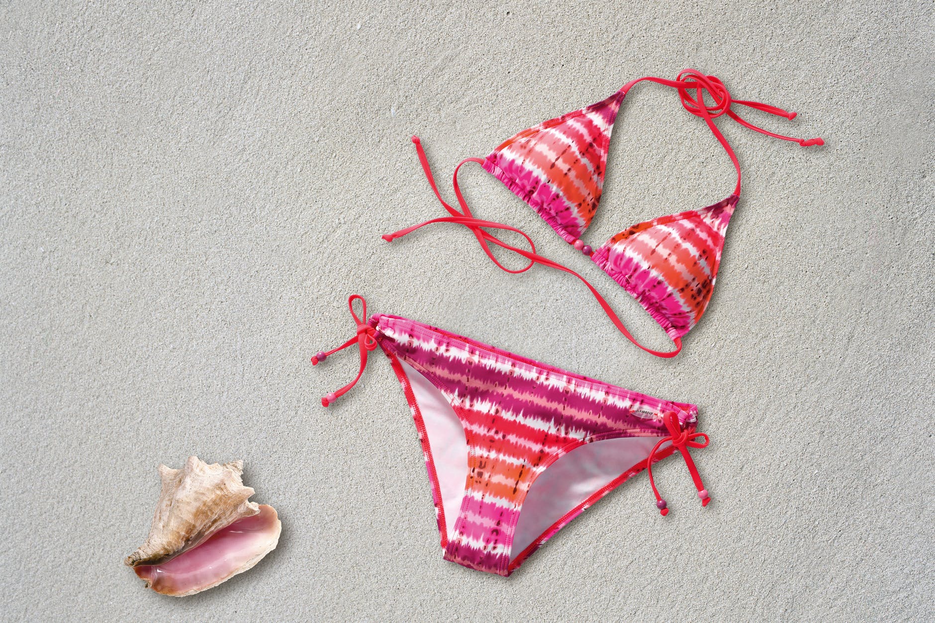 orange pink white stripe bikini near shell on sand beach